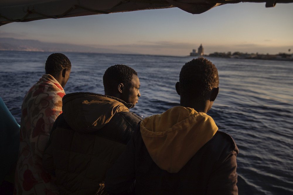 Uomini che sono stati salvati al largo delle coste libiche nel gennaio 2020 osservano la città di Messina, in Sicilia, dal ponte della nave di salvataggio Open Arms. 