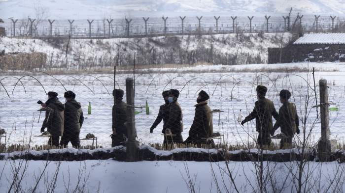 Uniformed border guards patrol next to a fence