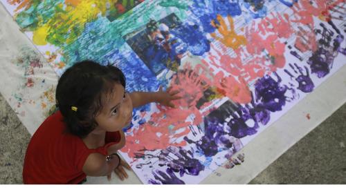 A girl covers anti-LGBT messages in rainbow handprints during a Pride rally in Manila on June 27, 2015.