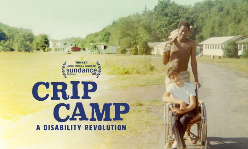 Poster do filme Crip Camp, mostra um monitor do acampamento ao atras de um menino em uma madeira de rodas ambos sonridos. Ao lado esquerdo da foto está escrito "Crip Camp: A Disability Revolution"