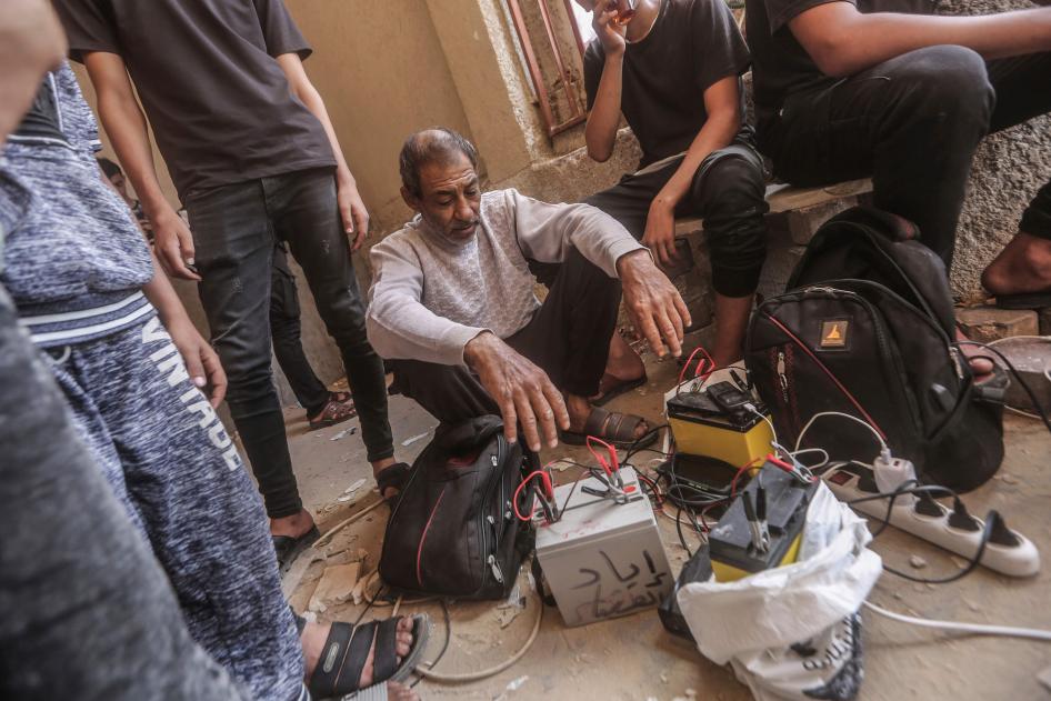 Des hommes palestiniens utilisaient des batteries de voitures pour recharger leurs téléphones portables, à Khan Yunis, dans le sud de la bande de Gaza,  le 23 octobre 2023.