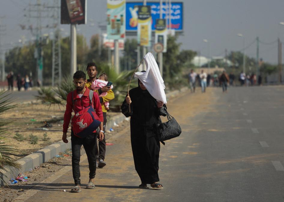 אישה אוחזת בדגל לבן ואזרחים פלסטינים נוספים בעת ההתפנות לכיוון דרום רצועת עזה, 7 בנובמבר 2023.