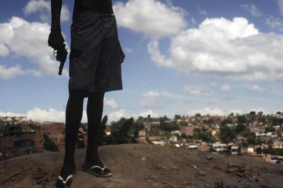 Um jovem brasileiro de 17 anos, membro de organização de tráfico de drogas, posa com uma arma no topo de um morro olhando para uma favela em Salvador, Bahia. 11 de abril de 2013.