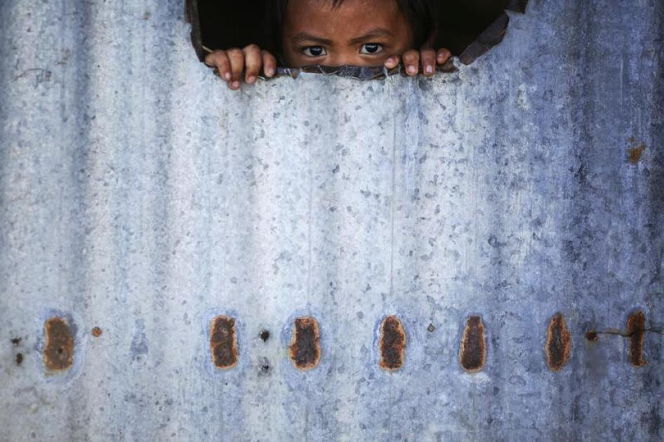 A child peers from inside a makeshift house with tin walls in Tacloban, Philippines, January 15, 2015.