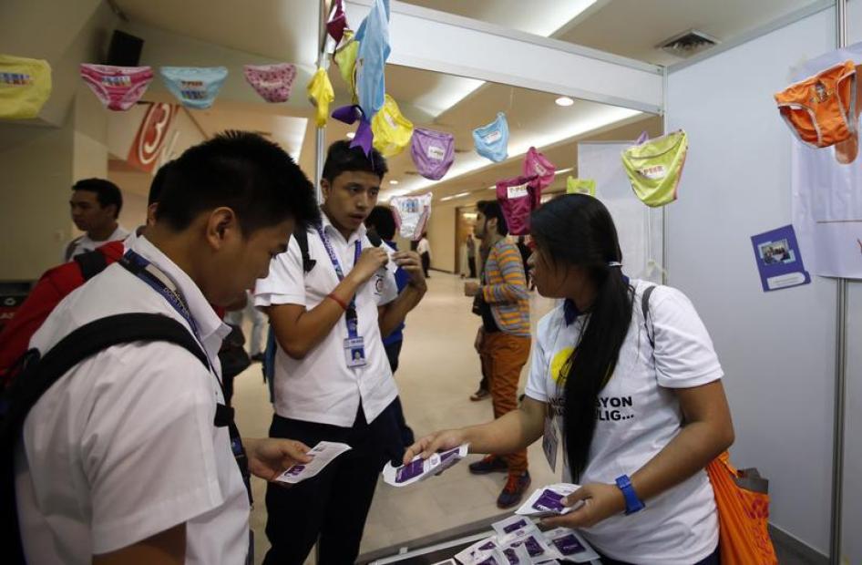 Students receive free condoms at an event organised by the United Nations Population Fund (UNFPA) on World Population Day, at a mall in Mandaluyong, Metro Manila, July 11, 2014.