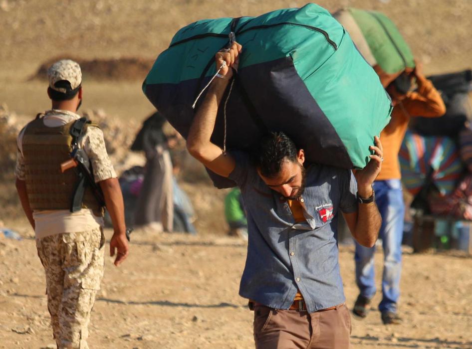 لاجئون سوريون يحملون متعلّقاتهم أثناء العودة إلى سوريا بعد عبور الحدود الأردنية قرب بلدة نصيب، في محافظة درعا الجنوبية. 29 أغسطس/آب 2017.