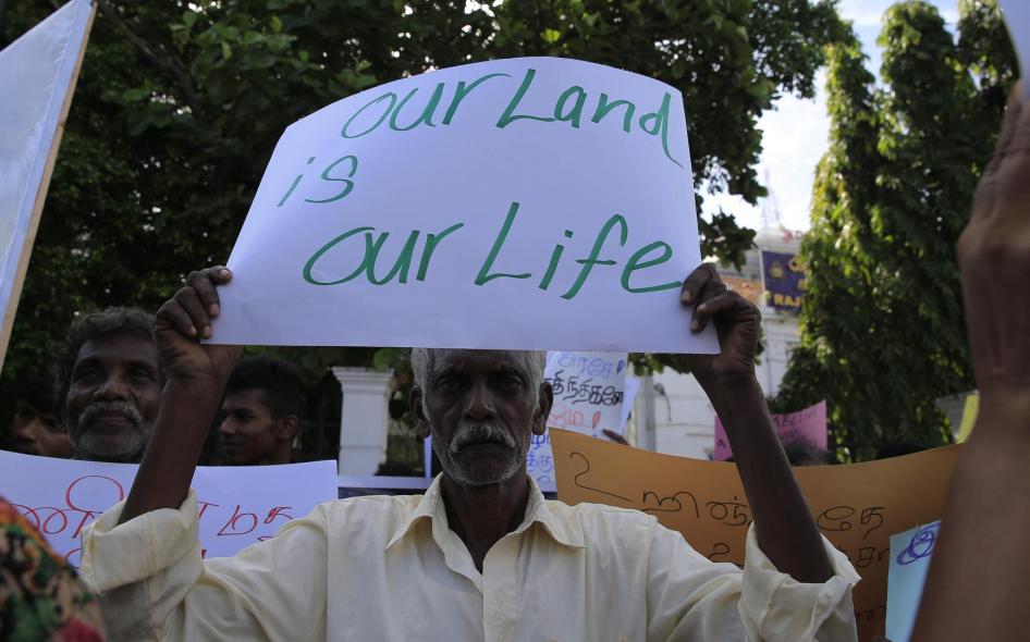 Seorang pria Tamil Sri Lanka memegang poster saat unjuk rasa di Kolombo pada 21 Agustus 2018, menuntut pembebasan tanah yang masih diduduki oleh militer. 