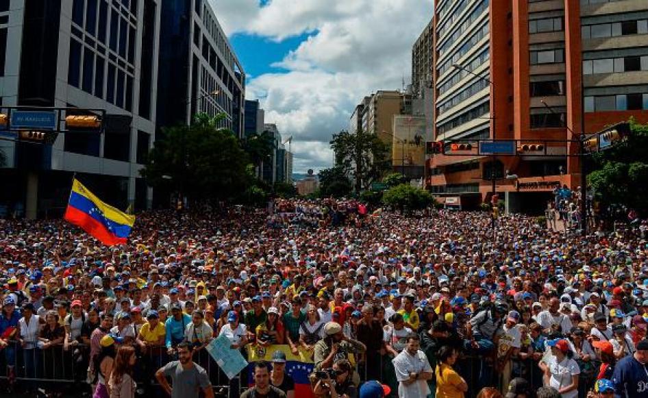 Une foule écoute le discours du président de l'Assemblée nationale du Venezuela, Juan Guaido (non visible sur la photo) lors d'un rassemblement massif de l'opposition contre le président Nicolas Maduro, à Caracas, le 23 janvier 2019. Ce rassemblement a ét