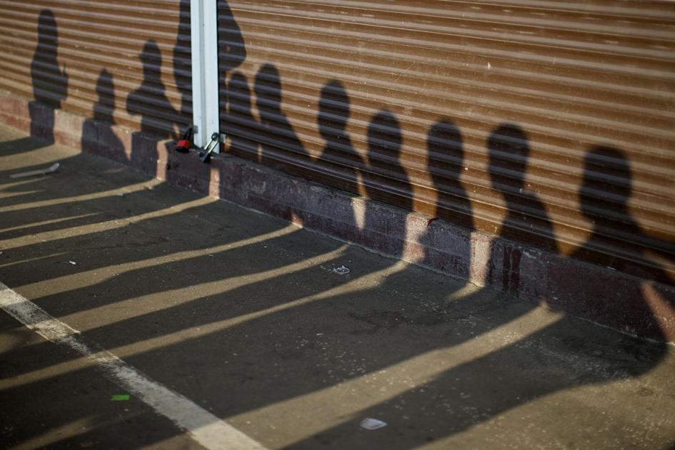Shadows of people detained by Russian police, suspected of violating immigration rules during an action seen on containers at a street market in Moscow, Russia, August 7, 2013. © AP Photo/Alexander Zemlianichenko