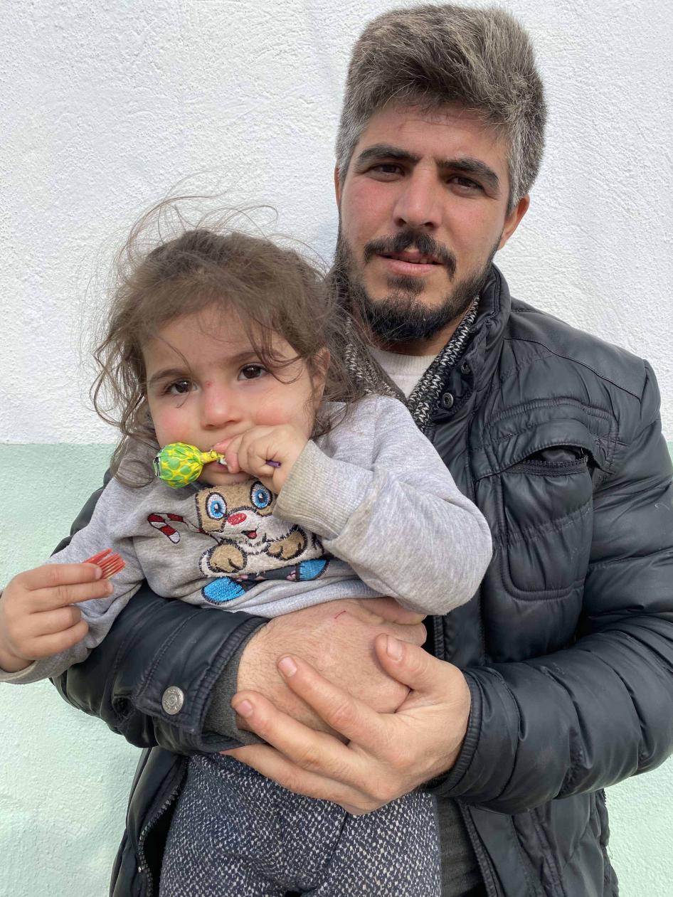 A Syrian man holds his 2-year-old daughter in the Turkish border village of Alibey on March 9, 2020, a day after he says Greek security forces detained and beat them both when he tried to stop them from sexually assaulting and stripping his wife.