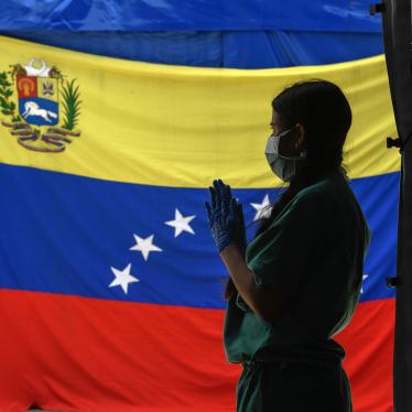 A staff member of Doctors Without Borders prepares herself as she waits for patients to be tested for Covid-19 in front of a Venezuelan flag at the Perez de Leon Hospital in the Petare neighbourhood, in eastern Caracas on June 23, 2020, amid the new coronavirus pandemic.