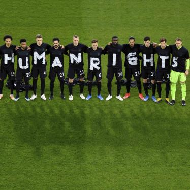 Soccer players stand in a line wearing shirts that spell out "HUMAN RIGHTS"