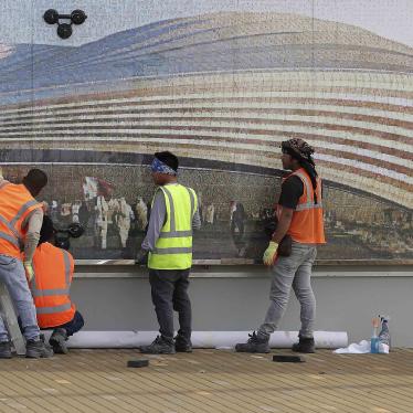 Workers in front of a mural of a stadium 