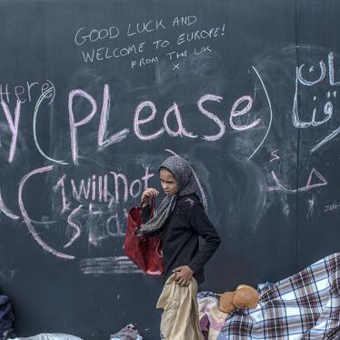 A young refugee girl walks past graffiti at the Keleti train station in Budapest