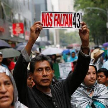 A protester holds up a sign next to relatives of some of the 43 missing students of Ayotzinapa College Raul Isidro Burgos during a march in Mexico City