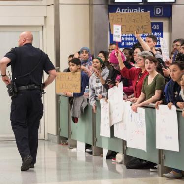 A police officer walks past people as they gather to protest against the travel ban imposed by U.S. President Donald Trump's executive order, at Dallas/Fort Worth International Airport in Dallas, Texas, U.S. January 28, 2017.
