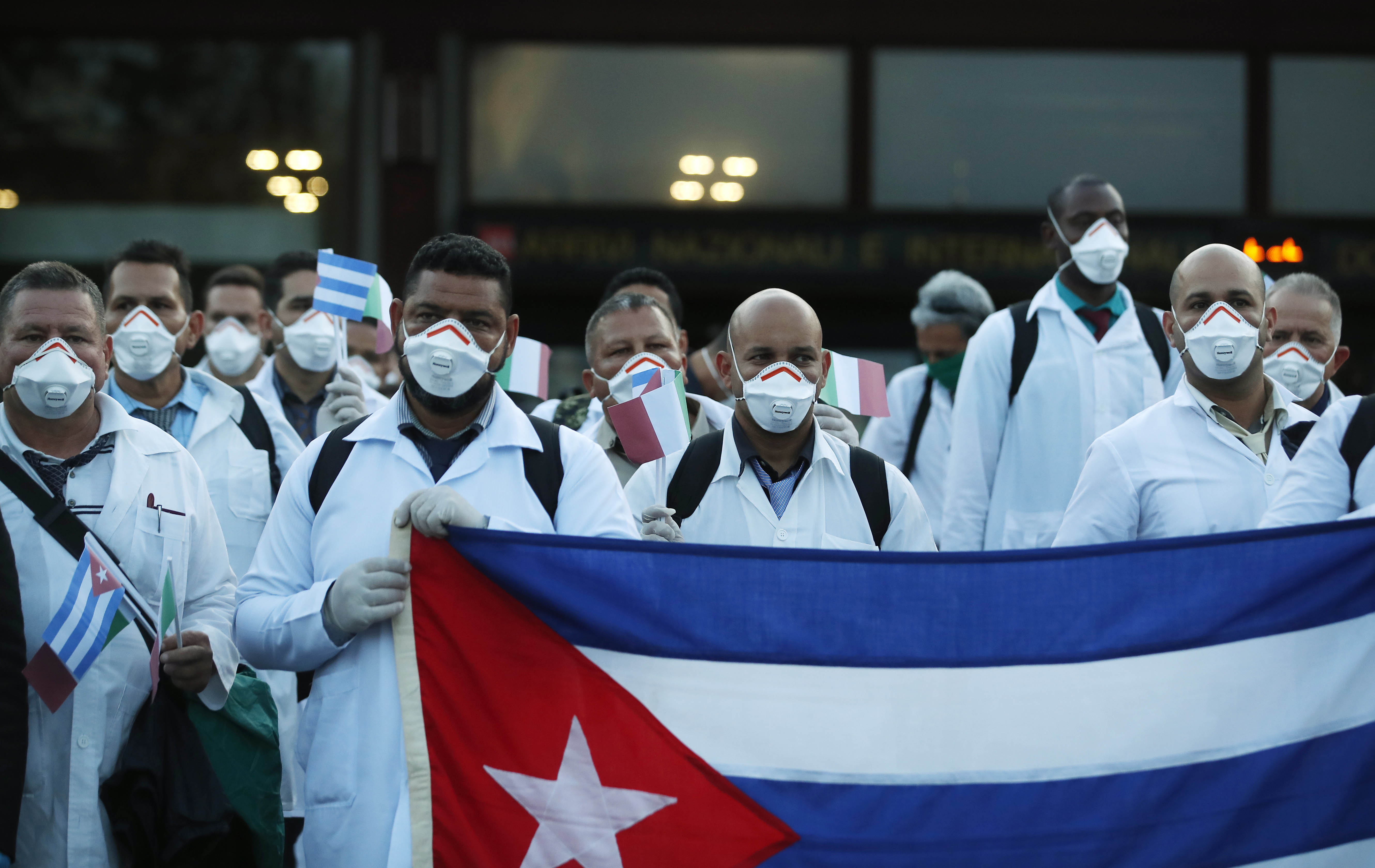 Medics and paramedics from Cuba pose upon arrival at the Malpensa airport of Milan, Italy, Sunday, March 22, 2020. Fifty-three doctors and paramedics from Cuba arrived in Milan to help with coronavirus treatment.