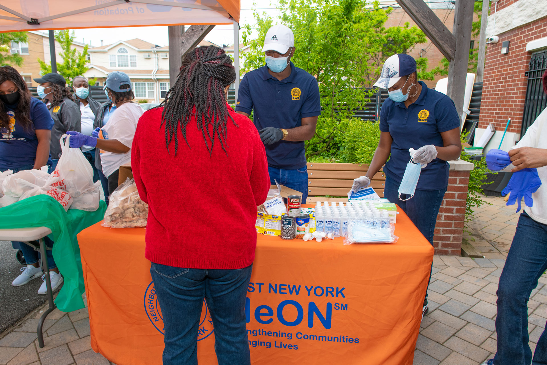 People distribute food and necessities to a woman at a table set up by the New York Department of Probation