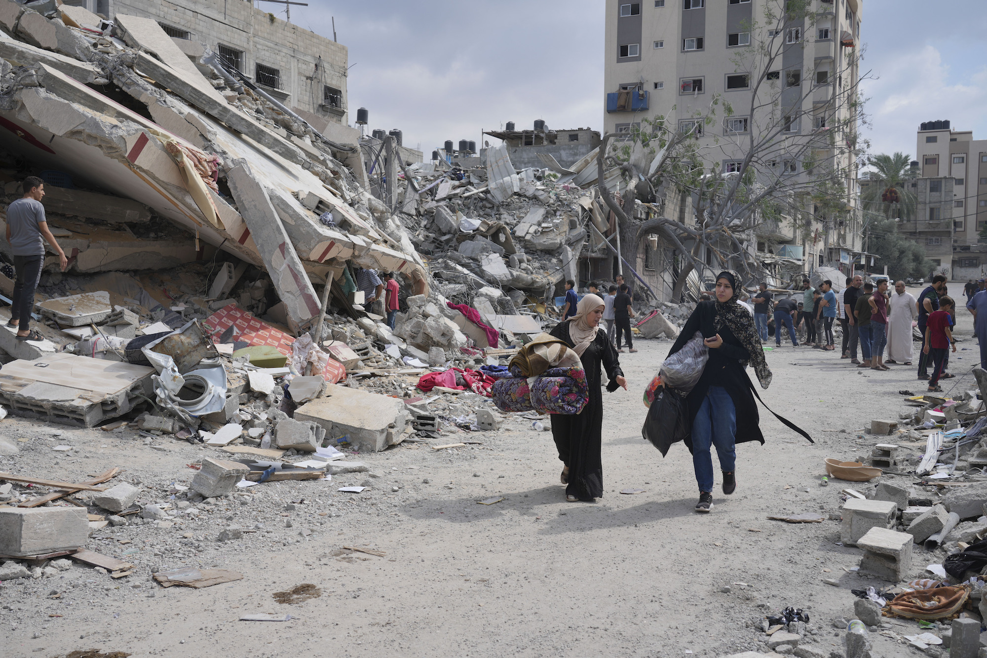 Deux femmes palestiniennes marchaient près de décombres de bâtiments détruits par des frappes aériennes israéliennes dans le camp de Nuseirat, situé vers le centre de la bande de Gaza, le 16 octobre 2023. 
