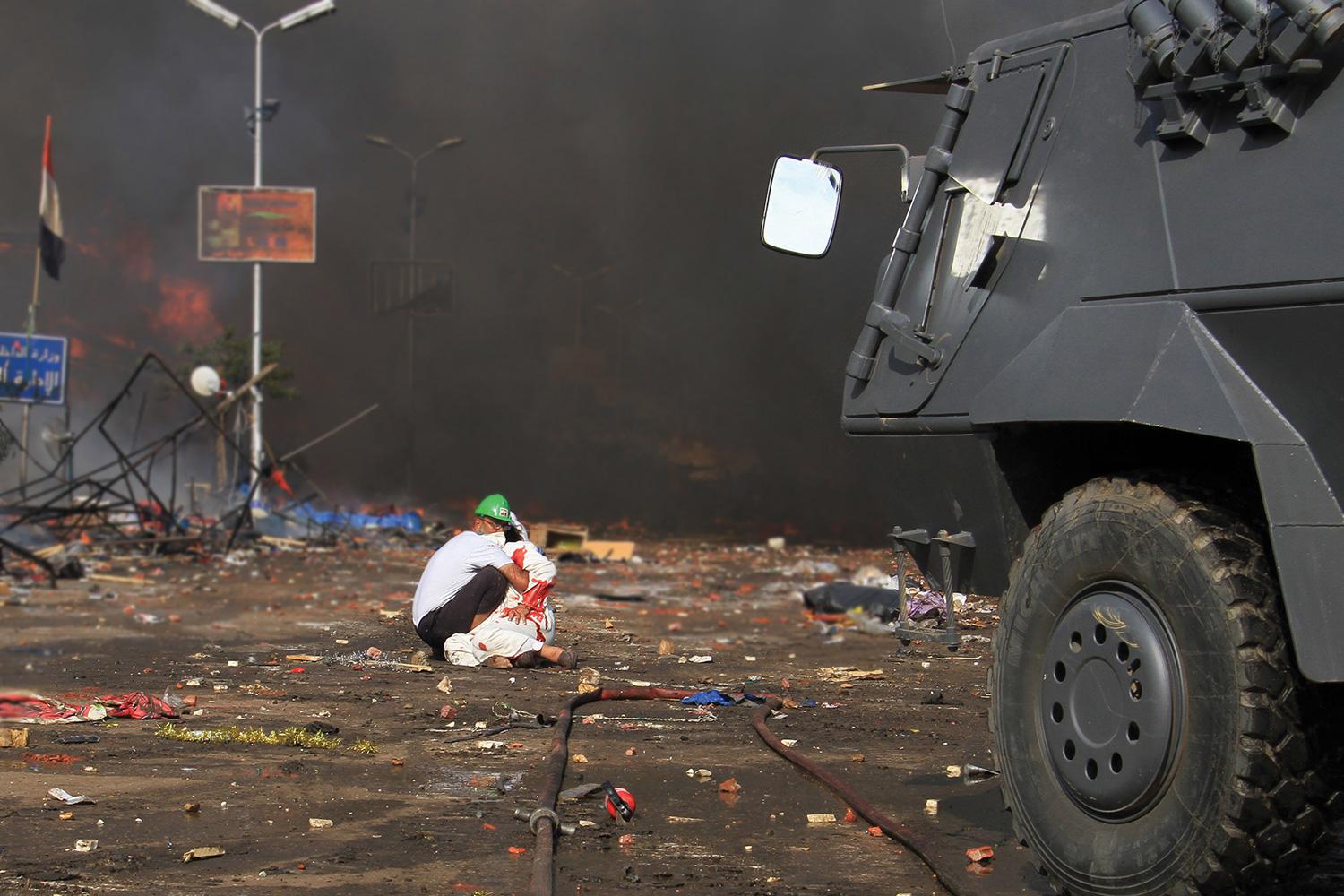 A volunteer tends to an injured demonstrator in front of a police armored personnel carrier (APC) in Rab’a Square in Cairo, Egypt on August 14, 2013.