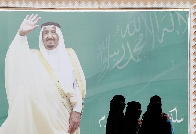 Para perempuan berjalan melewati sebuah poster Raja Arab Saudi, Salman bin Abdulaziz Al Saud, Riyad, Arab Saudi, 12 Februari, 2018.