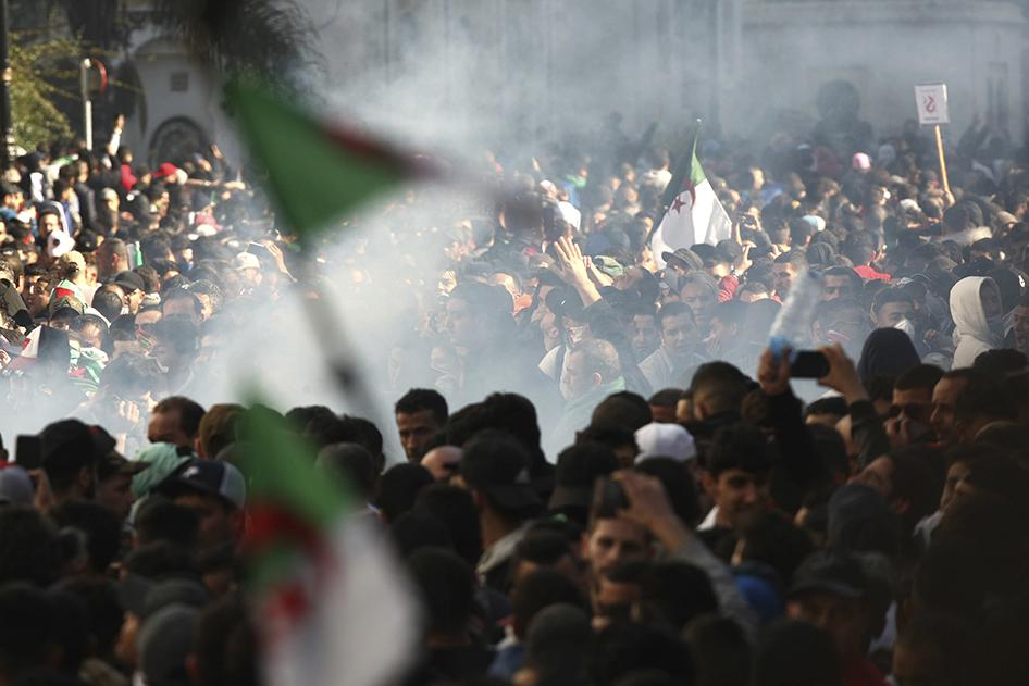 Des manifestants opposés à la candidature du président algérien Abdelaziz Bouteflika à un cinquième mandat défilent à Alger sous un nuage de gaz lacrymogène tiré par des policiers anti-émeute, le 1er mars 2019.