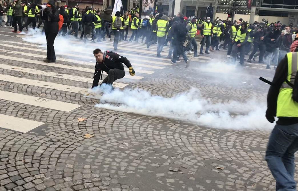 Un manifestant ramasse une grenade lacrymogène lors d'une charge de police, le 8 décembre 2019 sur les Champs Elysées, à Paris.