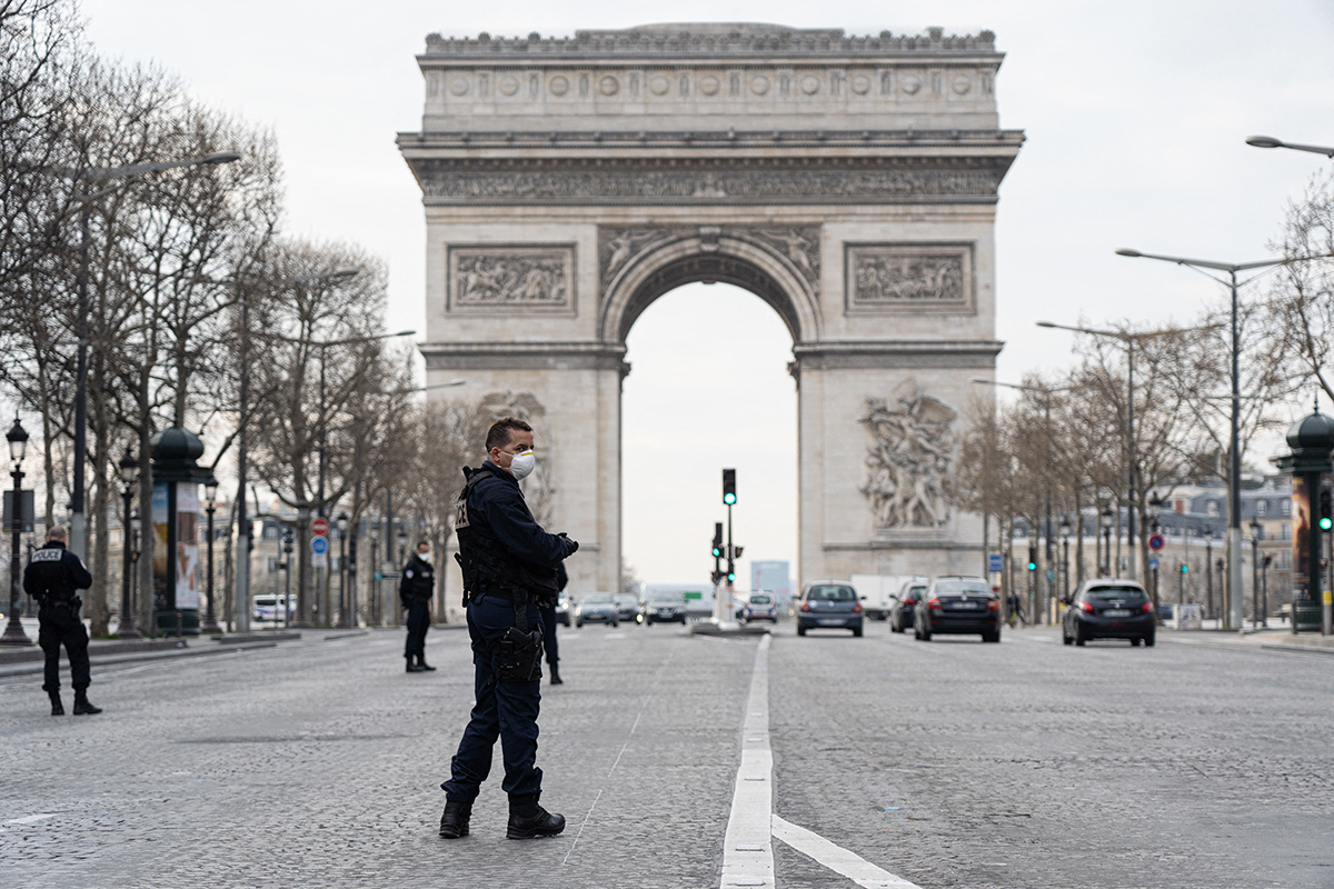 Des policiers patrouillent sur les Champs-Elysées devant l'Arc de Triomphe à Paris, le 17 mars 2020, premier jour de la période de confinement général décrétée par le gouvernement français en raison de la pandémie de COVID-19.