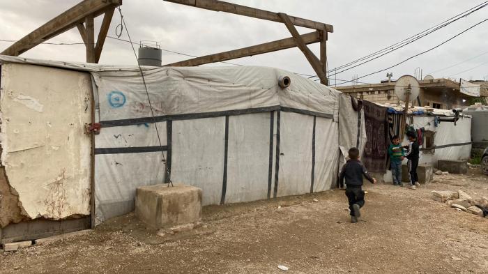 Children play next to shelters in a Syrian refugee camp in Arsal, Lebanon. Around 15,000 Syrian refugees in Arsal are entering their second winter without adequate roofs and insulation since the 2019 directive ordered them to dismantle concrete shelters and rebuild the top portion with tarp and wood. November 2020.