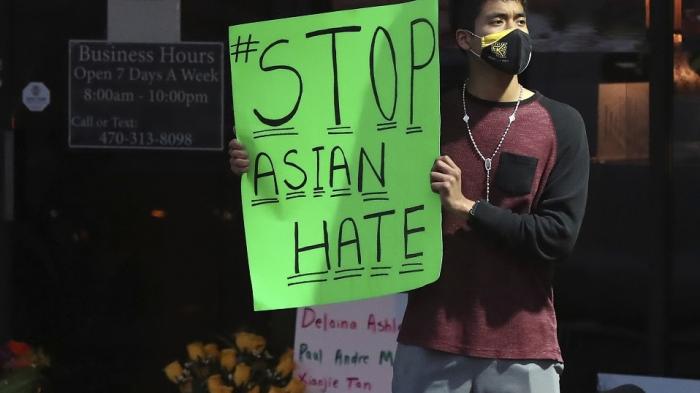 A man holds a sign reading “#StopAsianHate” outside Youngs Asian Massage in Acworth, Georgia on March 17, 2021, where four people were fatally shot the day before. 