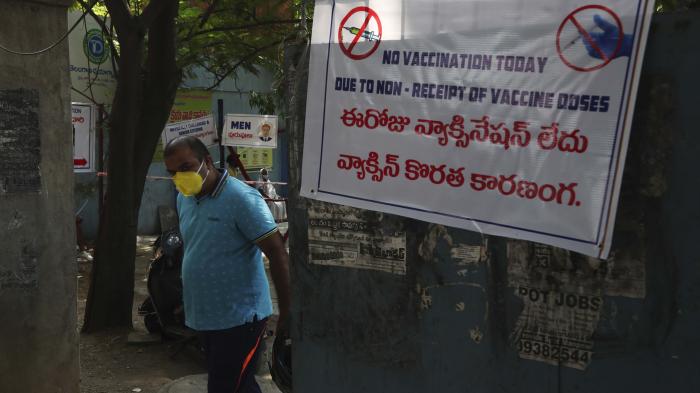 A man in a face mask stands next to a sign that says "No vaccination today" in English and Hindi