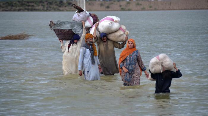 A displaced family wades through a flooded area after heavy rainfall in Jaffarabad, in Pakistan's southwestern Balochistan province.
