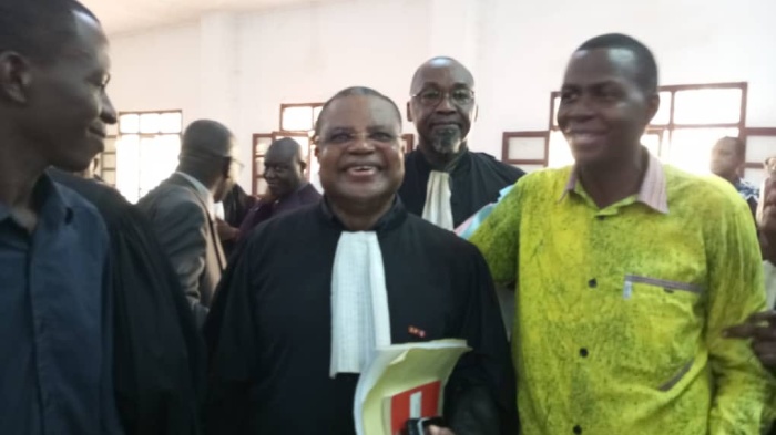 3 men stand smiling in a court room 