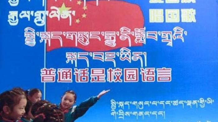 中国发给西藏各地小学的宣传海报。内容：“爱国旗，唱国歌。普通话是校园语言。请说普通话，请写规范字。”