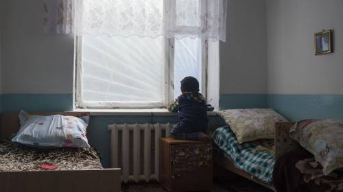 A child stares out a bedroom window