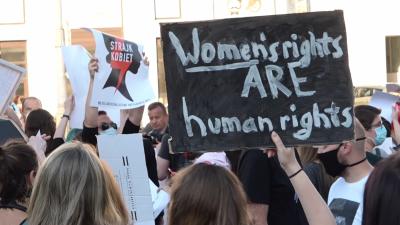 Demonstrantinnen erinnern mit einem Protestschild daran, dass Frauenrechte Menschenrechte sind.