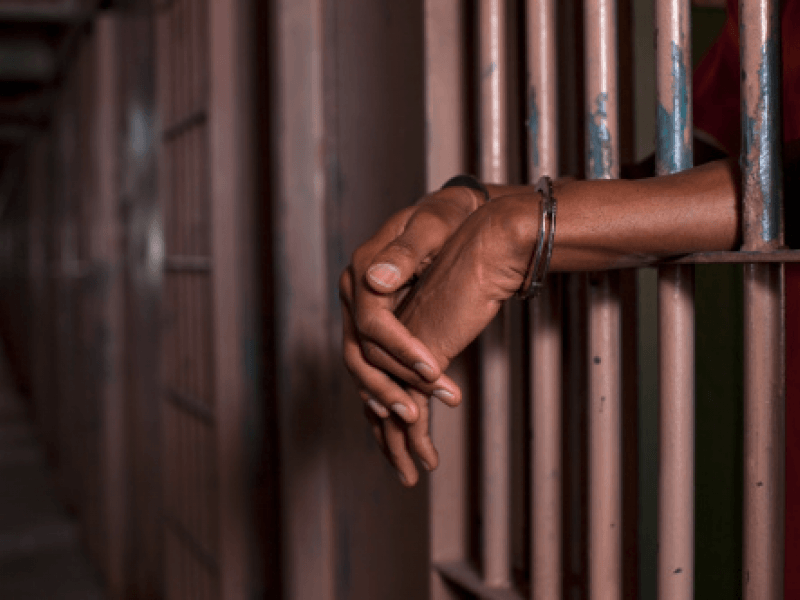 hands sticking through bars of a jail