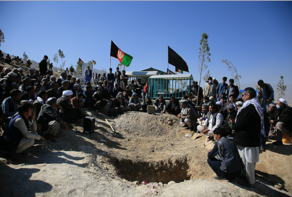 Des hommes accroupis se recueillent sur le site de l’enterrement de l’une des victimes de l'attentat suicide qui a visé une école à Kaboul, en Afghanistan, le 25 octobre 2020. 