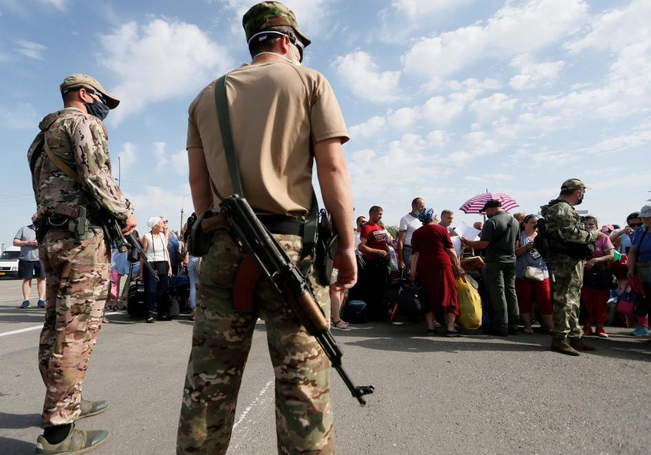 Озброєні люди з самопроголошеної «Донецької народної республіки» стоять на сторожі, поки люди чекають перетину лінії розмежування на КПВВ