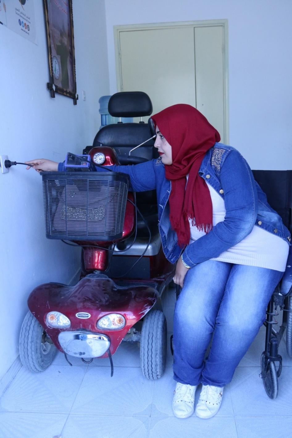 دعاء قشلان، امرأة عمرها 30 عاما لديها إعاقة حركية، تشحن السكوتر  في غزة. قالت لـ هيومن رايتس ووتش: "انقطاع الكهرباء هو أكبر مخاوفي. أحتاج إلى شحن السكوتر، وإلّا أُضطرّ إلى ملازمة المنزل، حيث أشعر أنّ الحياة توقّفت".