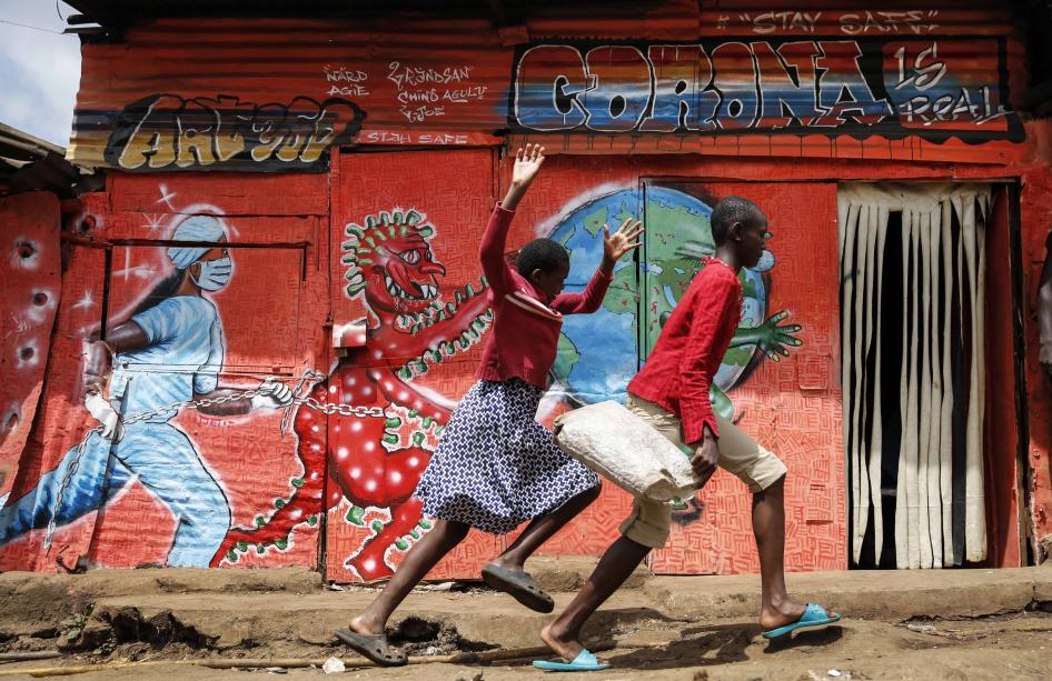 Children run past a mural that warns people about the dangers of the new coronavirus, in the Kibera informal settlement of Nairobi, Kenya.