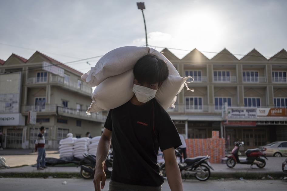A resident of a Red Zone carries bags of rice donated to his house during the coronavirus pandemic.