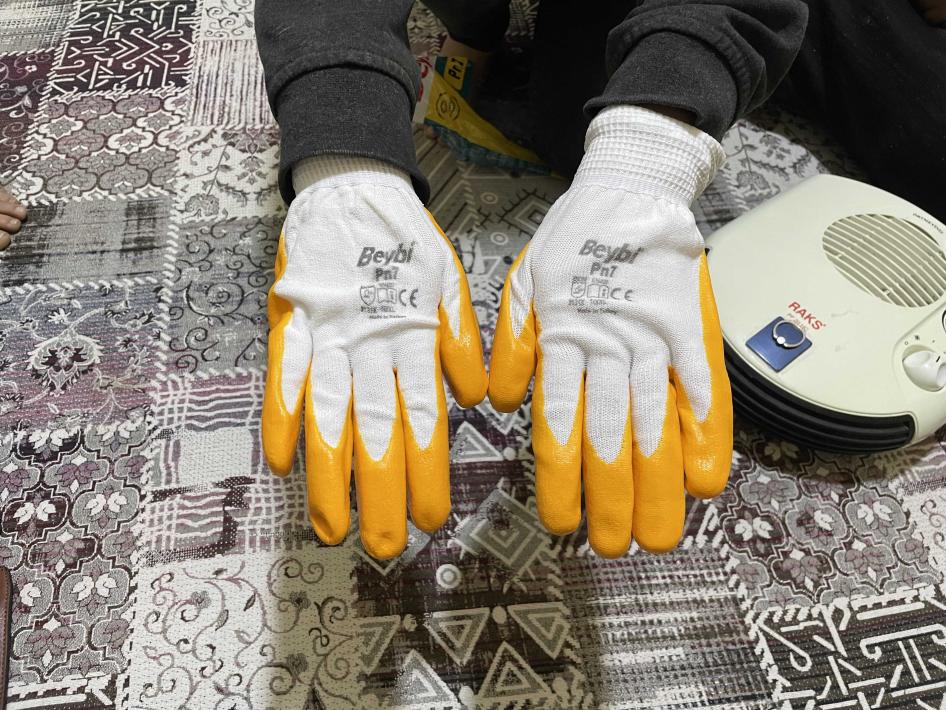 A person displays a pair of gloves