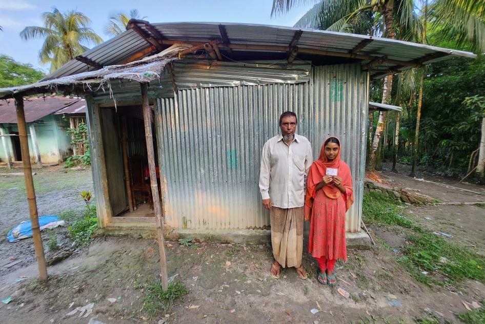 A man and his daughter stand in front of their house