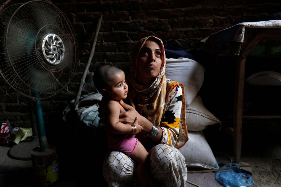A mother and child sit in front of a fan