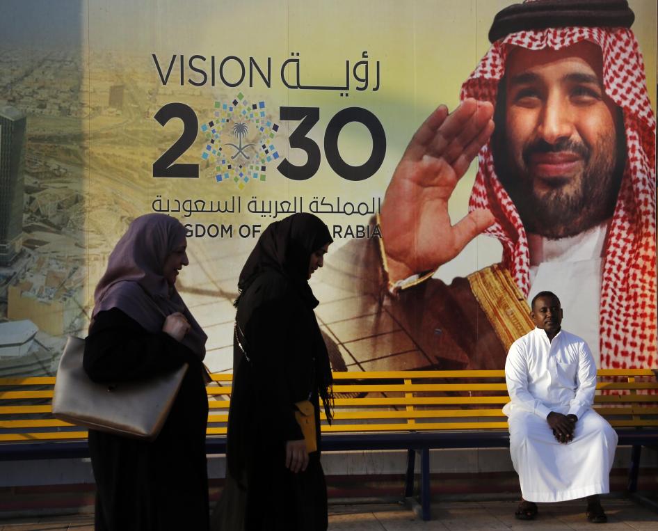 Orang-orang berjalan melewati spanduk Visi 2030 yang menunjukkan Putra Mahkota Saudi Mohammed bin Salman, Jeddah.  