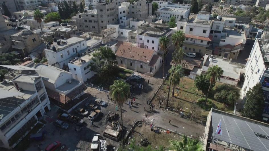 Eine Luftaufnahme des Geländes des Al-Ahli Krankenhauses. Der Krater ist auf dem Weg zwischen den beiden Grünanlagen zu sehen. An den Autos auf dem angrenzenden Parkplatz sind Brandschäden zu erkennen, Gaza-Stadt, 17. Oktober 2023.