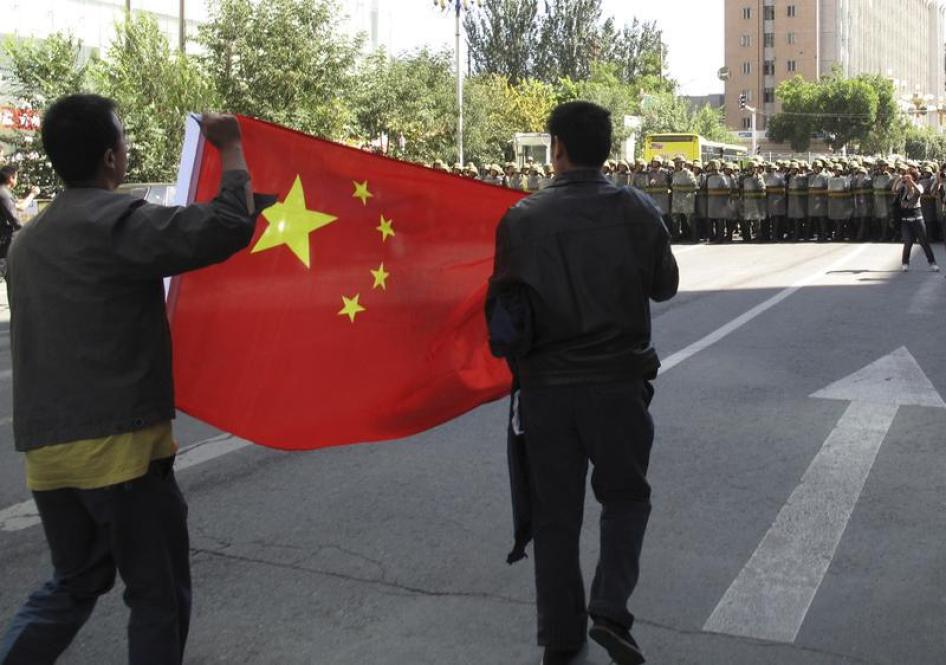 汉族民众拉起中国国旗走在乌鲁木齐市中心，前方路口被武警封锁，中国新疆自治区，2009年9月3日。