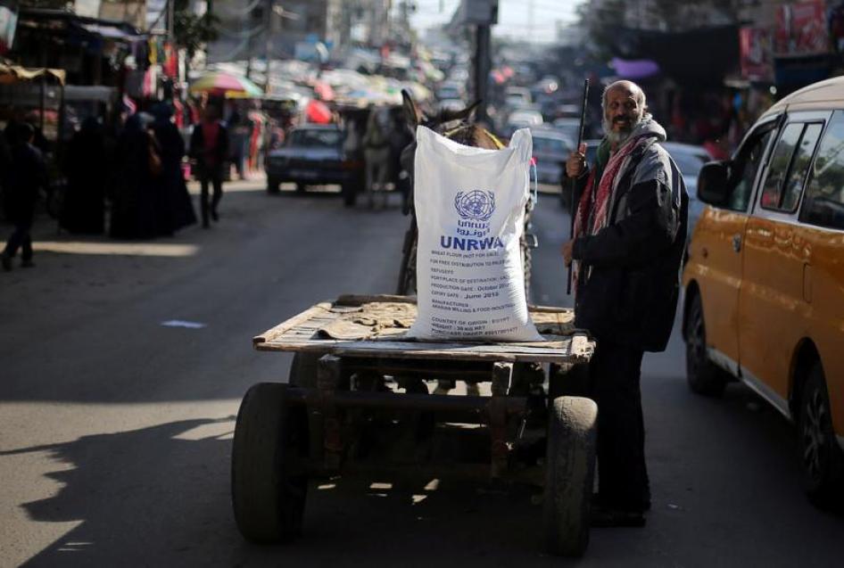  رجل فلسطيني يقف بجانب عربة تحمل كيس طحين وزعته "الأونروا" في مخيم خان يونس للاجئين في جنوب قطاع غزة، 3 يناير/كانون الثاني 2018. © 2018 رويترز 