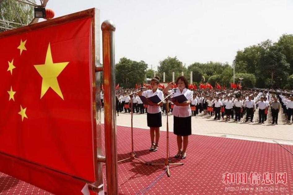 Deux jeunes femmes participent à une cérémonie de masse dans la préfecture de Hotan, dans la province du Xinjiang en Chine, lors de laquelle des milliers d’étudiants et enseignants de Hotan se sont engagés à respecter la « patrie » chinoise.